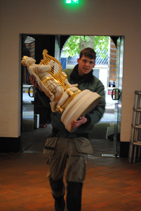 849292 Afbeelding van een medewerker van orgelmaker Hans van Rossum die het beeld van Koning David draagt tijdens het ...